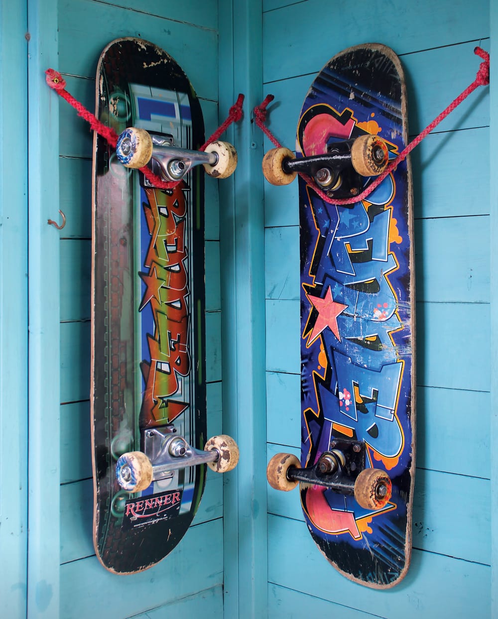 Two skateboards mounted on the wall using a loop of rope.